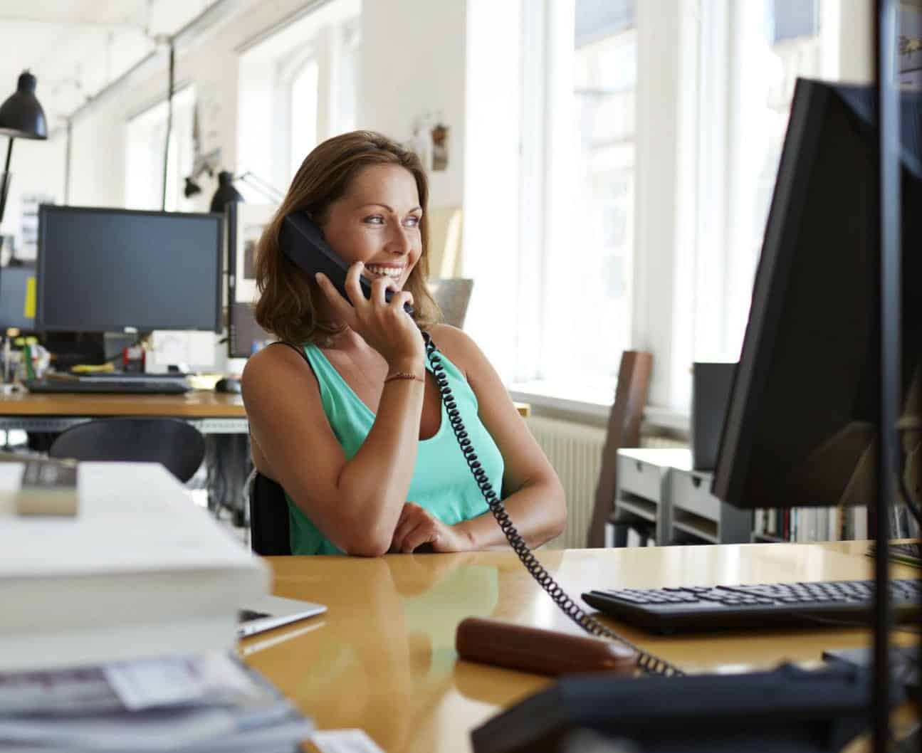 smiling lady on the phone at an office desk