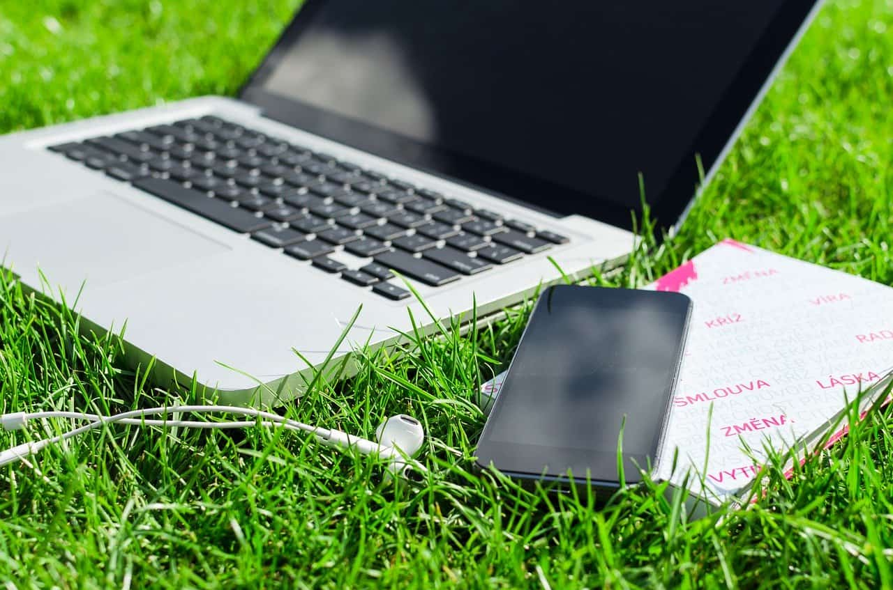 laptop, earphones and phone on green grass