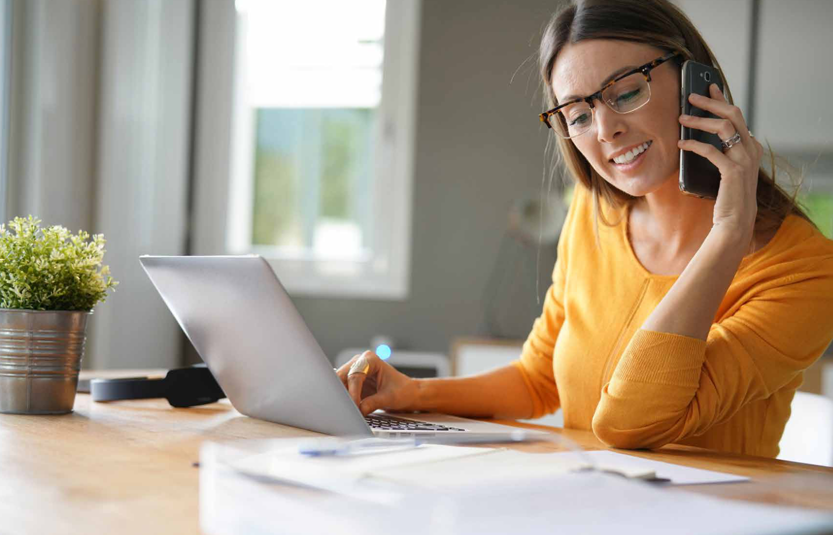 woman using a mobile phone working at a laptop