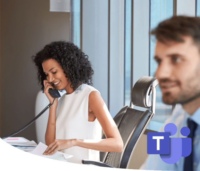 two people in a meeting room with woman taking a phone call