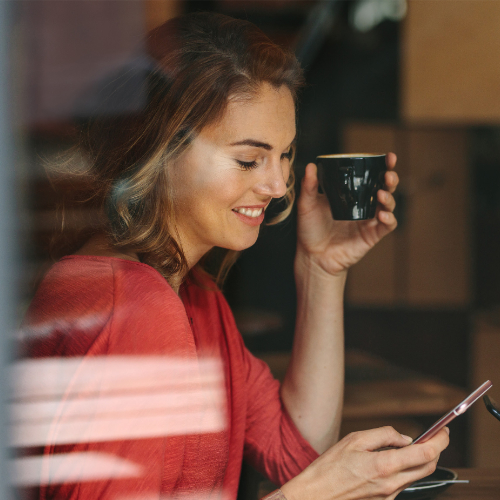 Microsoft Teams Phone - woman holding a cup of coffee and making a call on her mobile phone